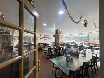 a man sitting at a table in a restaurant at Hotel SilverLine Regency Munnar in Munnar