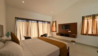 a hotel room with a bed and a flat screen tv at Banana Tree Retreat in Kodaikānāl