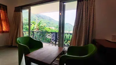 a room with a table and chairs and a large window at Banana Tree Retreat in Kodaikānāl