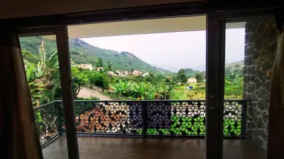 a room with a window with a view of a mountain at Banana Tree Retreat in Kodaikānāl