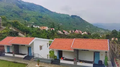 two white houses with red roofs on a mountain at Banana Tree Retreat in Kodaikānāl