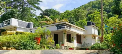 a small white house in front of a mountain at Mamalakandam - The White house, Diya homestay in Mamalakandam