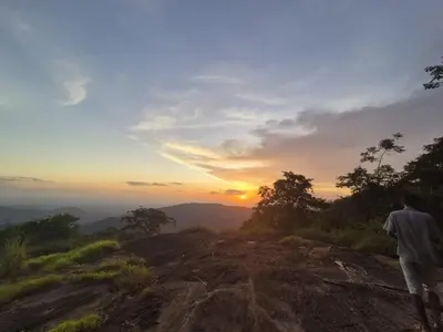 a man standing on top of a mountain looking at the sunset at Mamalakandam - The White house, Diya homestay in Mamalakandam