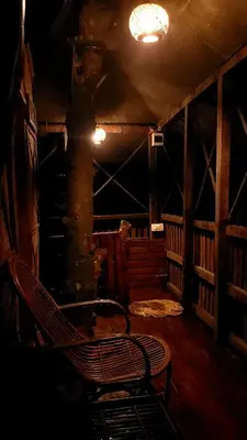 a dark room with a bench next to a tree at Greens Tree House & Wood House in Sultan Bathery
