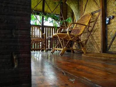 a group of chairs sitting on a porch at Greens Tree House & Wood House in Sultan Bathery