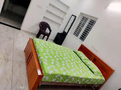 a bedroom with a green bed with a chair at Jeevakanthan Home Stay in Alāndurai