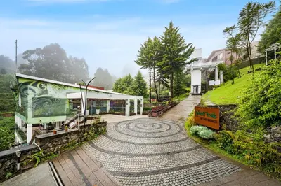 a cobblestone road leading to a building with a garden at GReaT Trails Kodaikanal by GRT Hotels in Kodaikānāl
