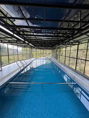 a large swimming pool with blue water in a building at Kosher Livings Holiday in Kalpetta