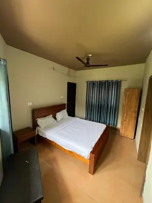 a bedroom with a large bed with white sheets at Kosher Livings Holiday in Kalpetta