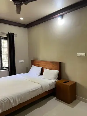 a bedroom with a large bed with a wooden headboard at Kosher Livings Holiday in Kalpetta