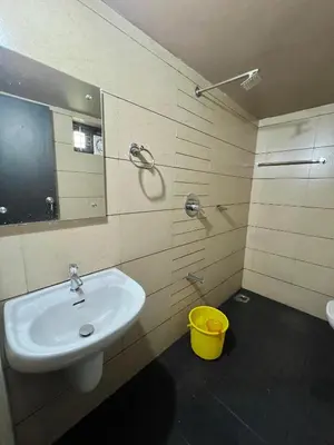 a bathroom with a sink and a mirror and a yellow bucket at Kosher Livings Holiday in Kalpetta