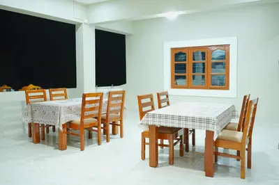 a dining room with tables and chairs and a blackboard at Athira Residency Coorg in Kushālnagar