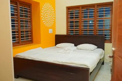 a bed in a room with orange walls and windows at Athira Residency Coorg in Kushālnagar