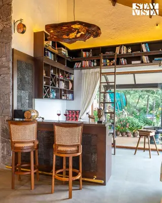 a kitchen with a bar with two chairs and a table at StayVista at Under the Stars Lovedale ooty in Ooty
