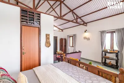 a bedroom with a bed and a wooden door at StayVista at Under the Stars Lovedale ooty in Ooty
