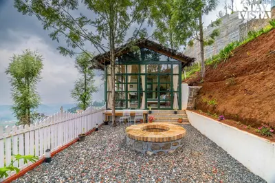 a glass building with a bench and a table at StayVista at Under the Stars Lovedale ooty in Ooty