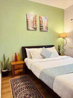 a bedroom with two beds and a green wall at Urban Lush in Ooty