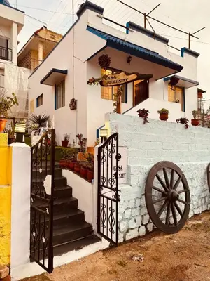 a white house with a gate and a cannon at Urban Lush in Ooty