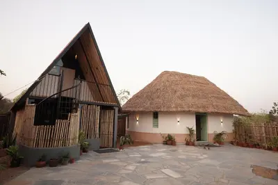 a house with a thatched roof and a courtyard at Moonrise Kingdom Permaculture Farm Stay in Hura