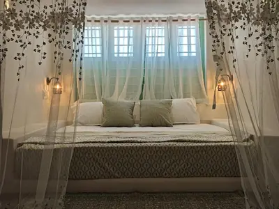 a bed in a room with curtains and a window at Moonrise Kingdom Permaculture Farm Stay in Hura