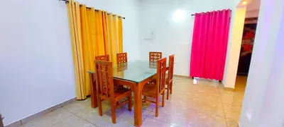 a dining room with a glass table and colorful curtains at Sands Villa Homestay in Wayanad