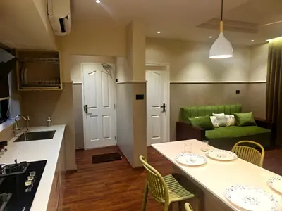 a kitchen and living room with a table and a green couch at Gulzar 1BHK Service Apartment, kannur in Kannur