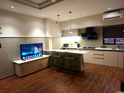 a kitchen with a counter with a bar with stools at Gulzar 1BHK Service Apartment, kannur in Kannur