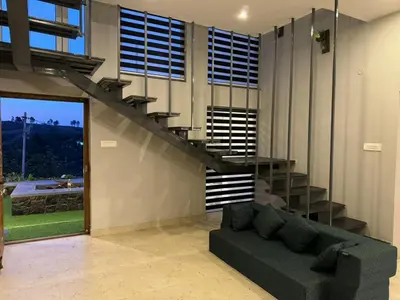 a living room with a couch and a staircase at blackdotstay-olive villa in Kodaikānāl