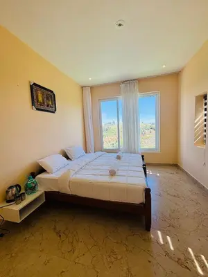 a bedroom with a large bed with a large window at blackdotstay-olive villa in Kodaikānāl
