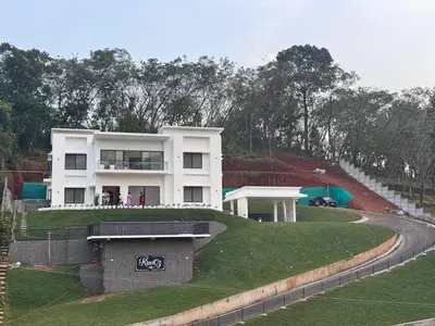 a white house on top of a green hill at KiwiOz Villa in Thamarassery