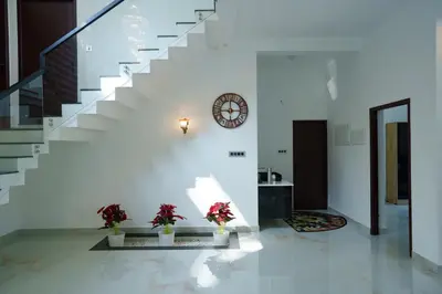 a staircase with two potted plants and a clock on the wall at KiwiOz Villa in Thamarassery