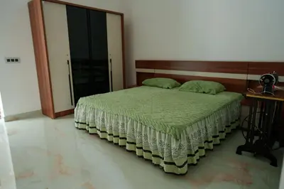 a bedroom with a bed with a wooden headboard at KiwiOz Villa in Thamarassery