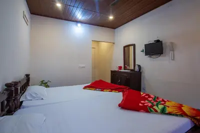 a bedroom with two beds and a tv on the wall at Misty Creek Homestay in Vālpārai