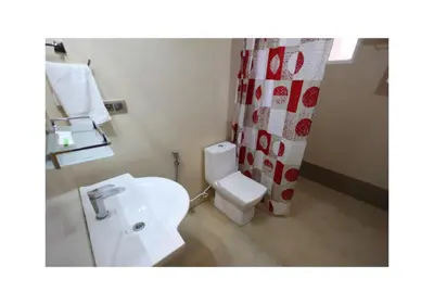 a bathroom with a white toilet and a shower curtain at The Forest Haven in Ooty