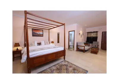 a bedroom with a canopy bed and a living room at The Forest Haven in Ooty