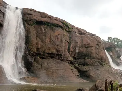 a waterfall on the side of a rocky mountain at Boganvilla, Magic Land Resort in Athirappilly