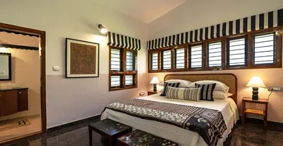 a bedroom with a bed and some windows at Villa Vani in Mysore