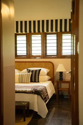 a bedroom with a bed with white pillows and windows at Villa Vani in Mysore