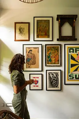 a woman looking at a bunch of pictures on a wall at Villa Vani in Mysore