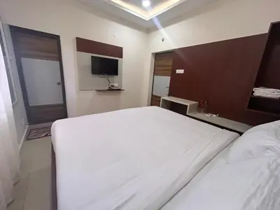 a bedroom with a large white bed and a television at Rio Grande Retreat in Kodaikānāl