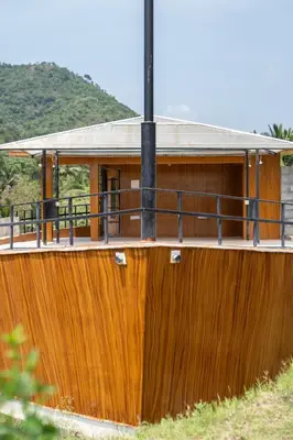 a wooden house with a balcony on top of it at Yanai at Anai - Private Pool & Private Cook in Varagampadi