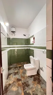 a bathroom with a white toilet and green walls at Wayanad Haven Villa in Wayanad