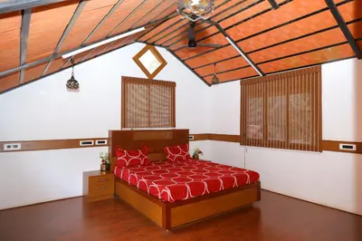 a bedroom with a bed with a red comforter at SS Farms By Shivalaya Stays in Alāndurai