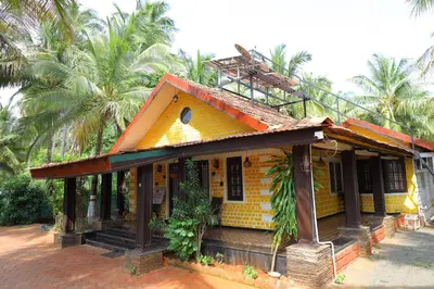 a small yellow house with palm trees in the background at SS Farms By Shivalaya Stays in Alāndurai
