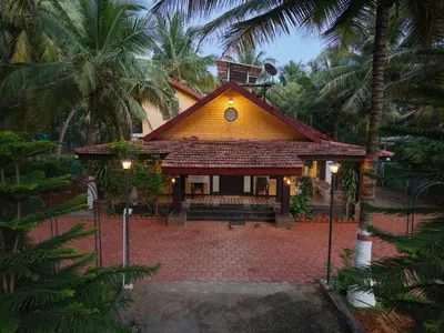 a small yellow house with palm trees in front of it at SS Farms By Shivalaya Stays in Alāndurai