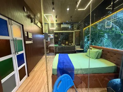 a bedroom with a bed and a glass wall at JOHNS VILLAGE Resorts in Vallikavungal