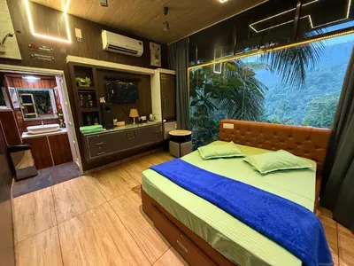 a bedroom with a bed and a large window at JOHNS VILLAGE Resorts in Vallikavungal