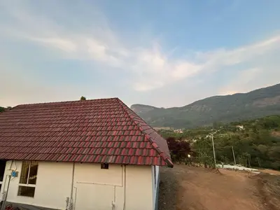 a house with a red roof with mountains in the background at Kashmir Valley Alpha in Kanthalloor