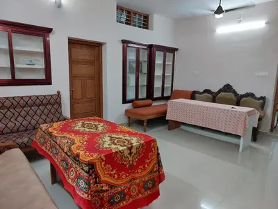 a room with two beds and a table and chairs at Real Estate GURUVAYOOR in Trichūr