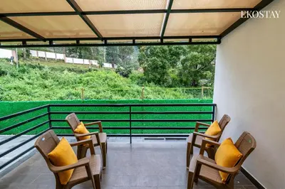 a group of chairs with yellow pillows on a balcony at EKOSTAY - Amber Villa in Kodaikānāl